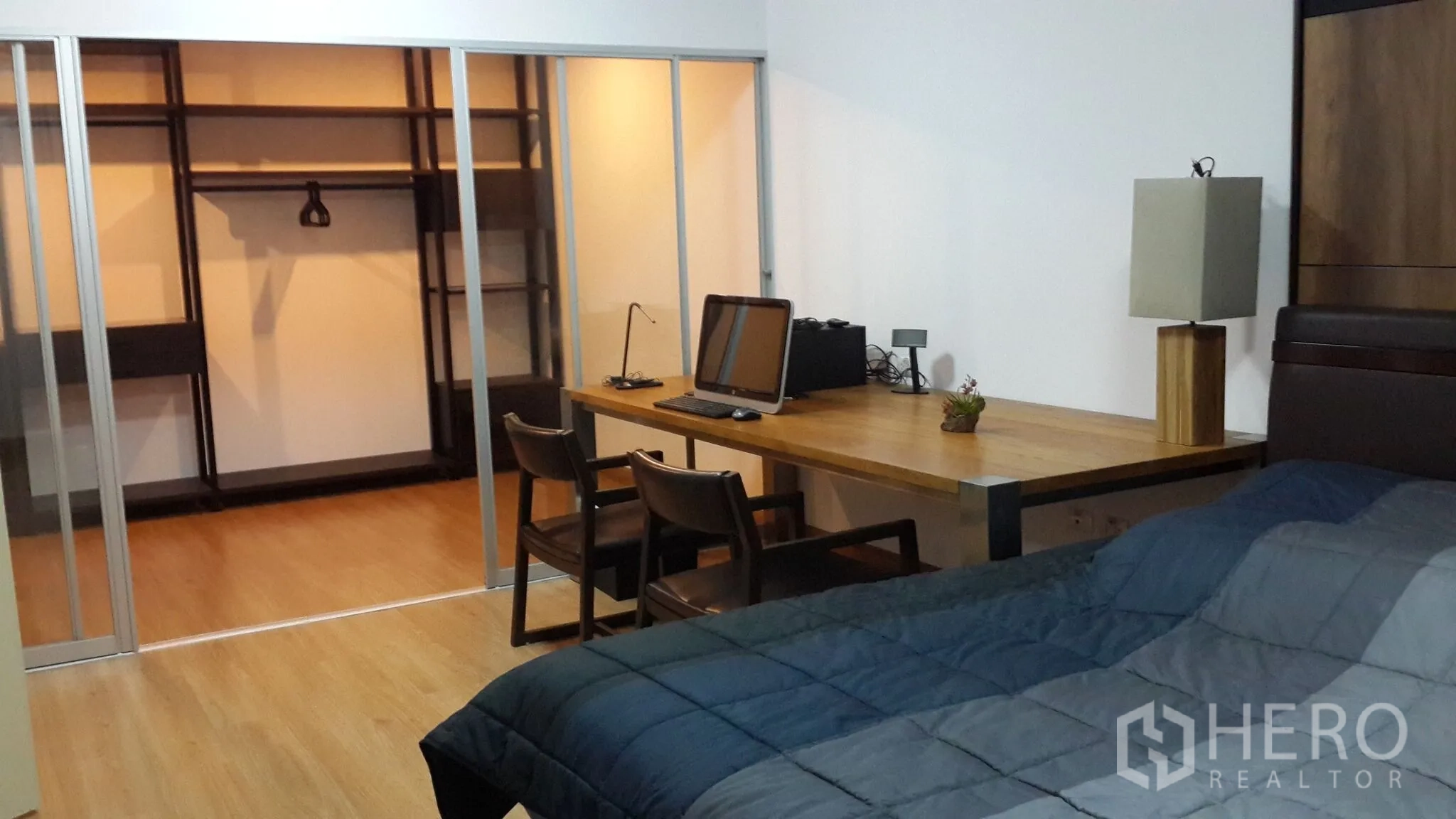 คอนโด ให้เช่าในHuai Khwang, Bangkok - ห้องนอนพร้อมเตียง ผ้าห่ม โต๊ะทำงานไม้ยาว และทางเข้าห้องแต่งตัวผ่านฉากกั้นกระจก