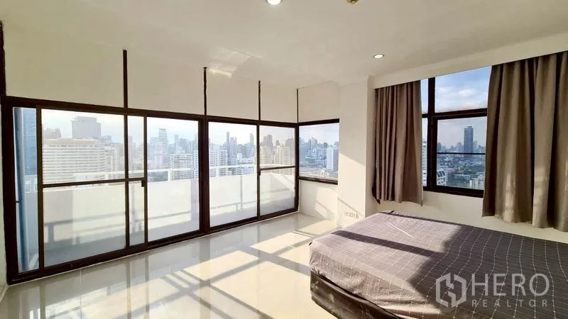 Condominium for rent in Watthana, Bangkok - Corner bedroom with wraparound windows and sliding doors to the balcony.