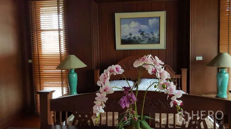 ทาวน์เฮาส์ ให้เช่าในKhlong Toei, Bangkok - ห้องนอนใหญ่ เตียงไม้แกะสลัก ผนังไม้ และโคมไฟข้างเตียง