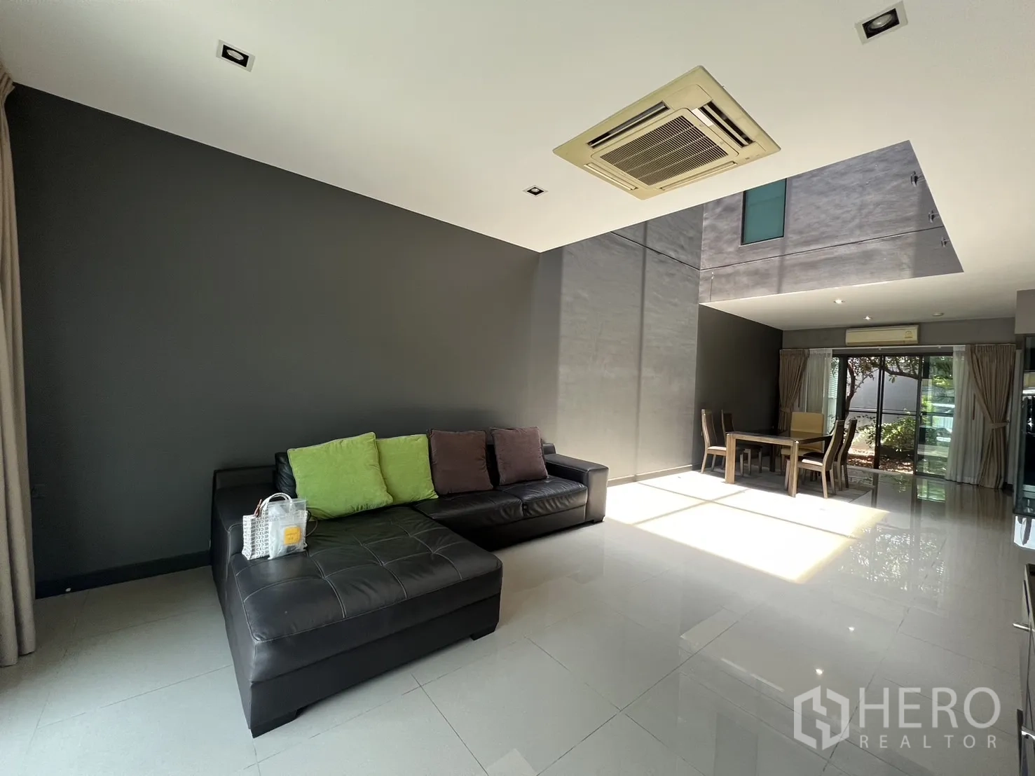 联排别墅 出租在Lat Phrao, Bangkok - 挑高客餐廳採光充足，落地窗與黑色皮沙發。