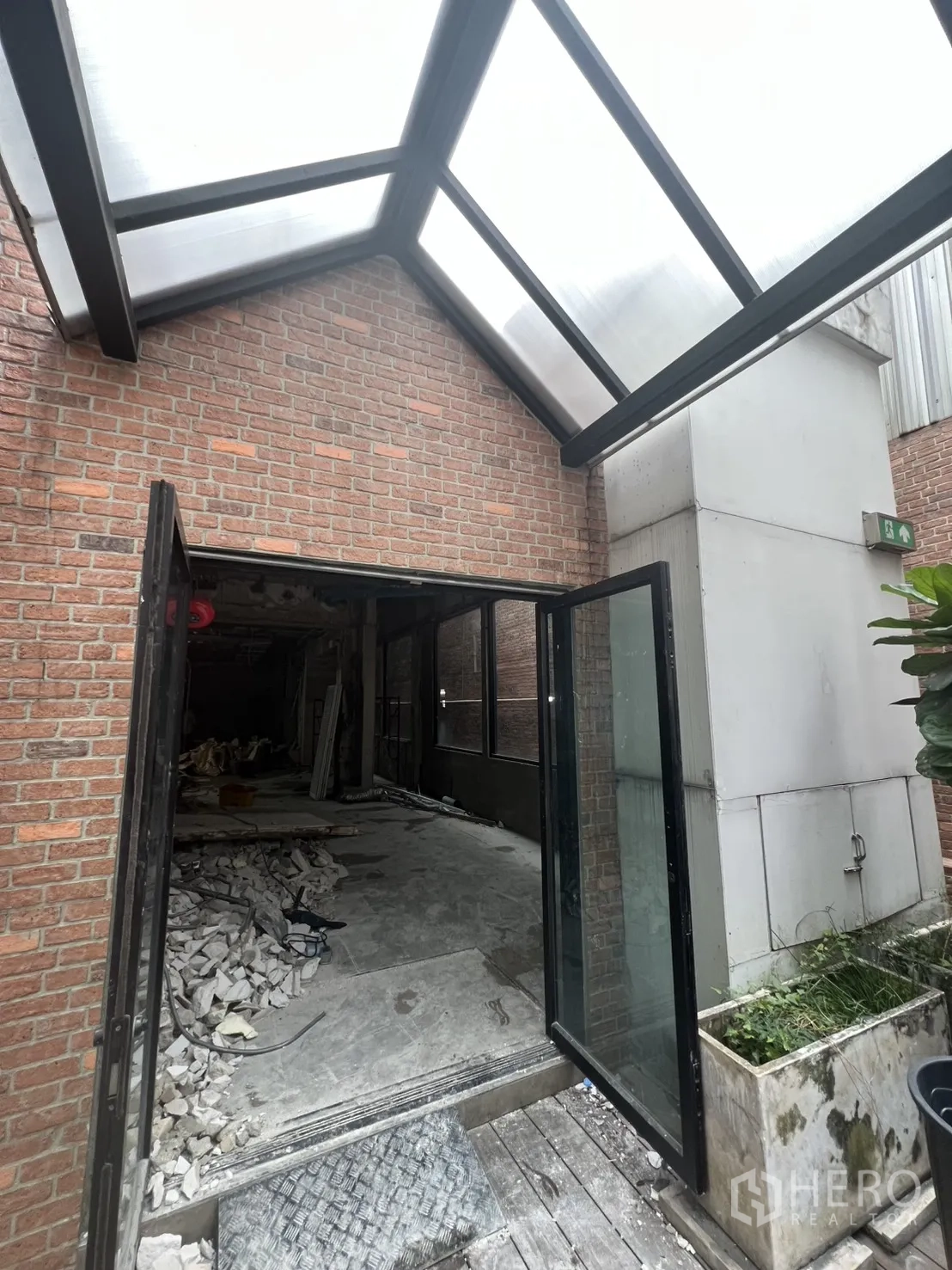 อาคารพาณิชย์ ให้เช่าในBang Rak, Bangkok - ประตูกระจกเปิดสู่พื้นที่ก่อสร้างใต้กันสาดโปร่งแสง มีเศษวัสดุ