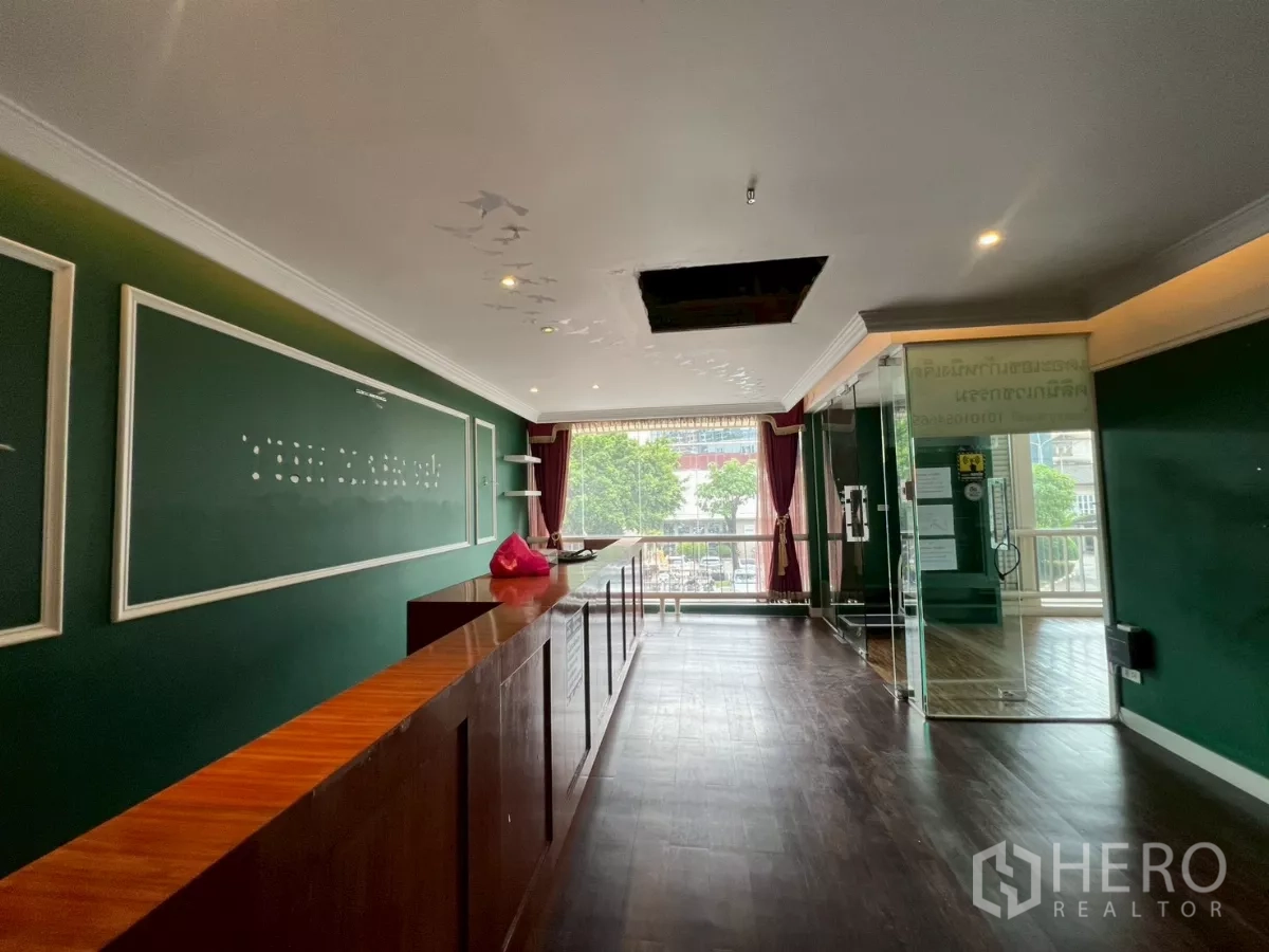 Office Space for rent in Watthana, Bangkok - Reception-style area with dark wood flooring, green feature walls, large front window and glass entrance suitable for office or retail.
