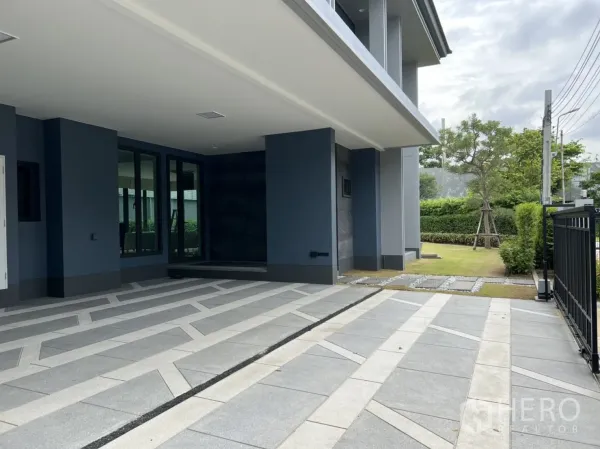 Detached House for rent in Bang Kapi, Bangkok - Covered driveway with patterned tiles opening to the garden and a black metal gate.